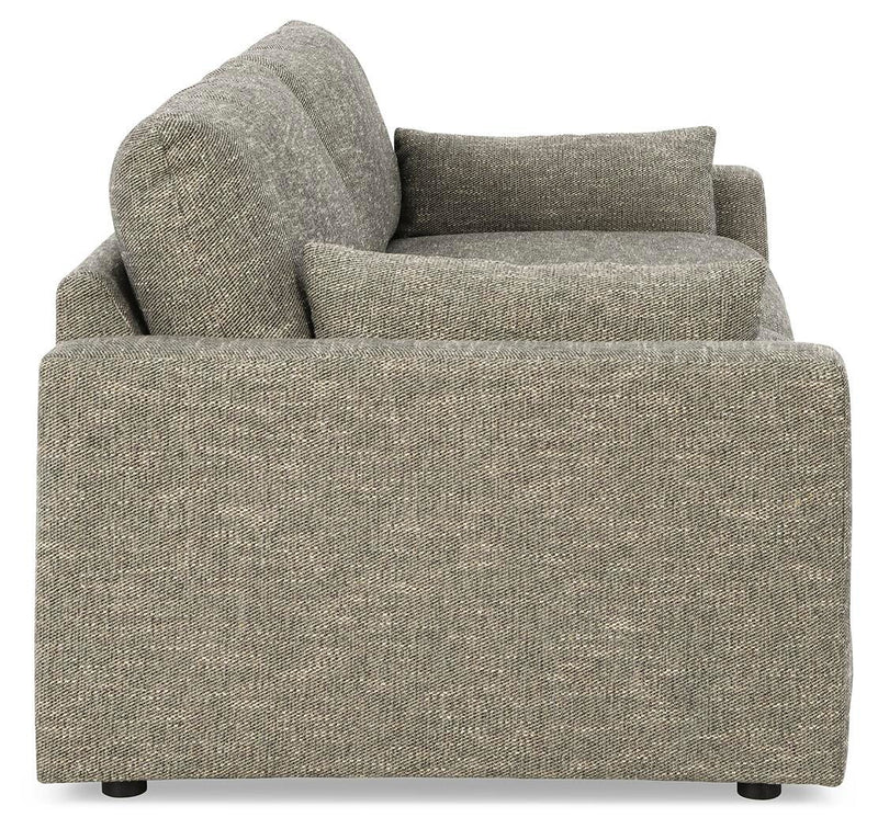 Ashley Furniture dramatic sofa with plush cushions and sleek design, shown from side angle in a modern living room setting.
