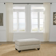 Ashley Furniture Asanti Ottoman with plush upholstered top and wooden legs, ideal for living room decor.