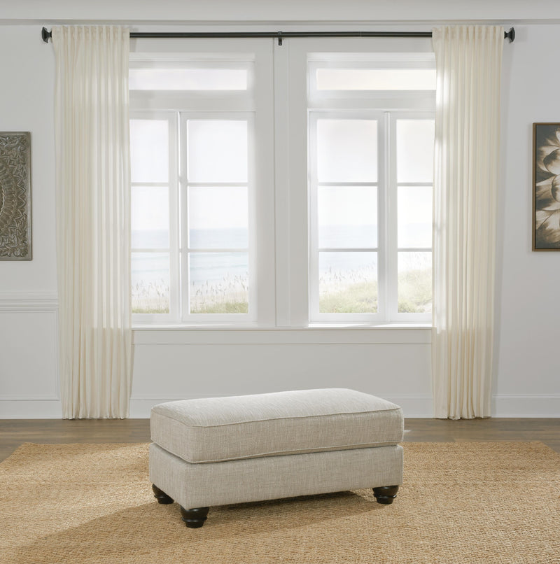 Ashley Furniture Asanti Ottoman with plush upholstered top and wooden legs, ideal for living room decor.