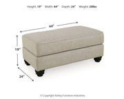 Ashley Furniture Asanti Ottoman with plush fabric and decorative wooden legs, ideal for living room or bedroom decor.