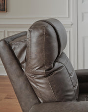 Ashley Furniture Schooner Rocks power recliner with plush upholstery and built-in headrest, shown in a comfortable, modern living room setting.