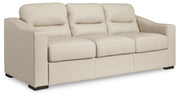 Ashley Furniture Treasure Trove sofa in beige fabric, angled view showing plush cushions and stylish armrests.