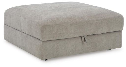 Ashley Furniture Aslan Court Ottoman with storage, upholstered beige fabric, open top, and wooden legs, shown from an angle.