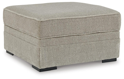 Ashley Furniture Calnita Ottoman with storage, showing a stylish fabric ottoman with a closed lid and wooden legs.