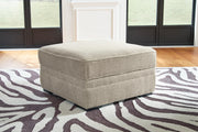 Ashley Furniture Calnita Ottoman with storage, beige fabric, sturdy wooden legs, and a padded top for versatile seating and storage.