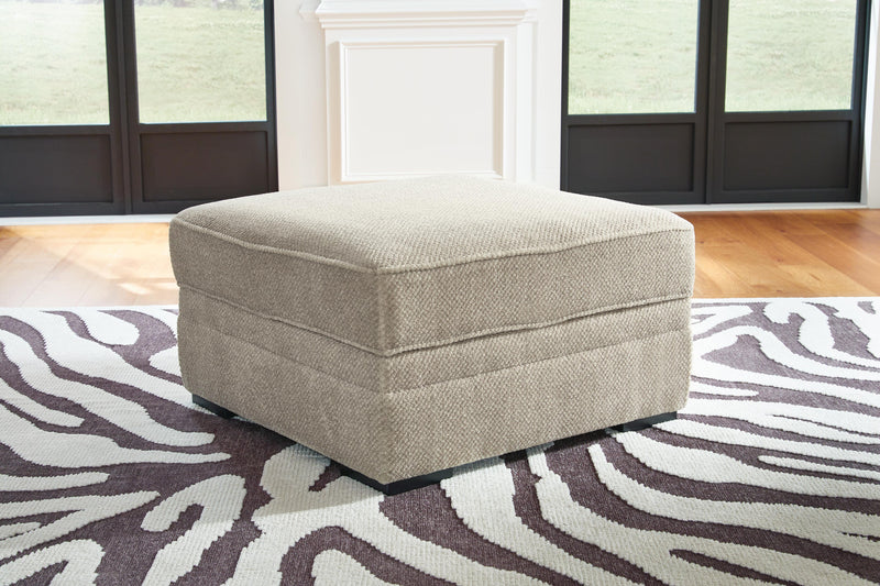 Ashley Furniture Calnita Ottoman with storage, beige fabric, sturdy wooden legs, and a padded top for versatile seating and storage.