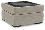 Ashley Furniture Calnita Ottoman with storage and cup holder, featuring a cushioned top and dark wood finish.