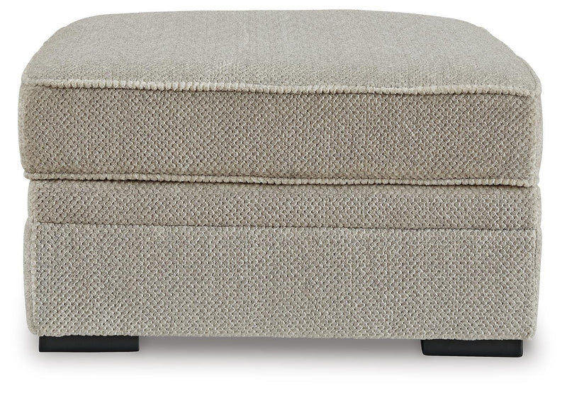 Ashley Furniture Calnita Ottoman with storage, featuring a plush fabric top and wooden legs, shown from a front head-on angle.