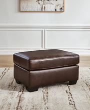 Ashley Furniture Santorine Ottoman showcasing a plush fabric surface and wooden legs in a cozy living room setting.