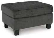 Ashley Furniture Erinslane Ottoman showing plush fabric and wooden legs from an angled view.