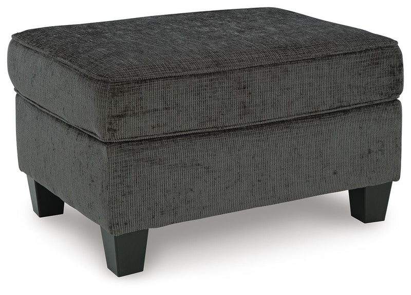 Ashley Furniture Erinslane Ottoman showing plush fabric and wooden legs from an angled view.