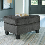 Ashley Furniture Erinslane Ottoman showing a wooden upholstered storage ottoman in a neutral fabric with decorative nailhead trim.
