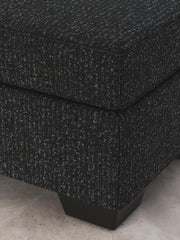 Ashley Furniture Jasmine Peaks Ottoman with plush fabric and wooden legs, shown in a detailed close-up image.