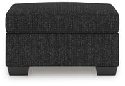 Ashley Furniture Jasmine Peaks Ottoman in neutral fabric, showcasing its plush cushioned top and wooden legs.