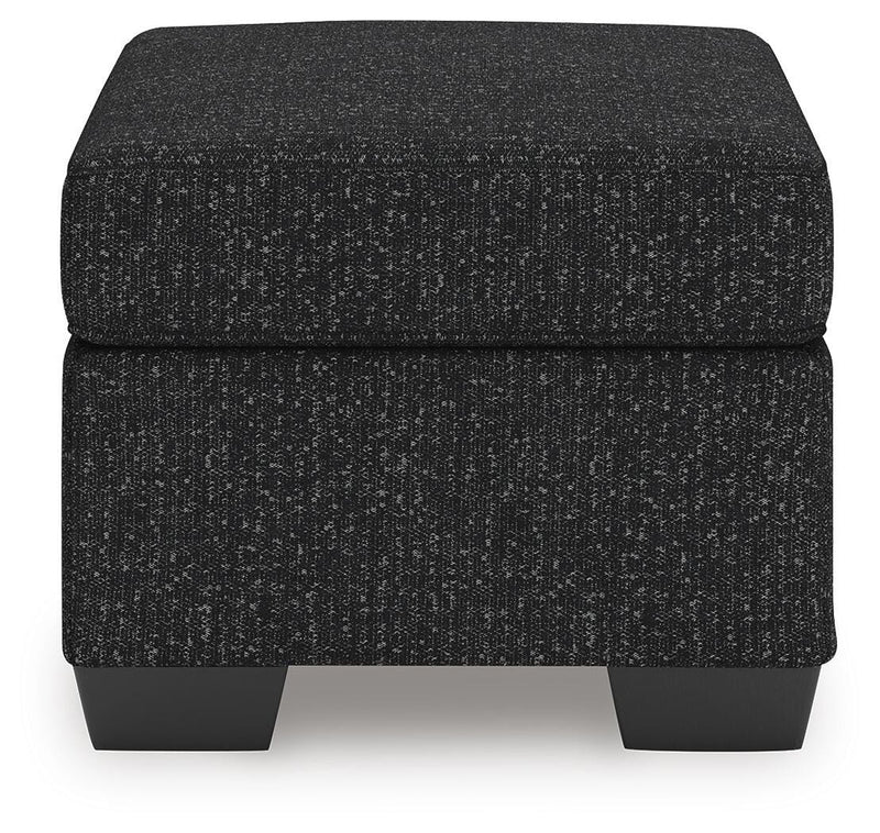 Ashley Furniture Jasmine Peaks Ottoman with fabric upholstery and wooden legs, shown from a side angle.