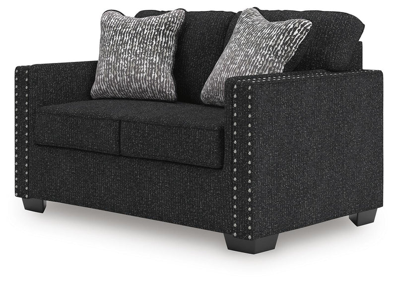 Ashley Furniture Jasmine Peaks loveseat shown from an angled side view, featuring plush fabric and cushioned armrests.