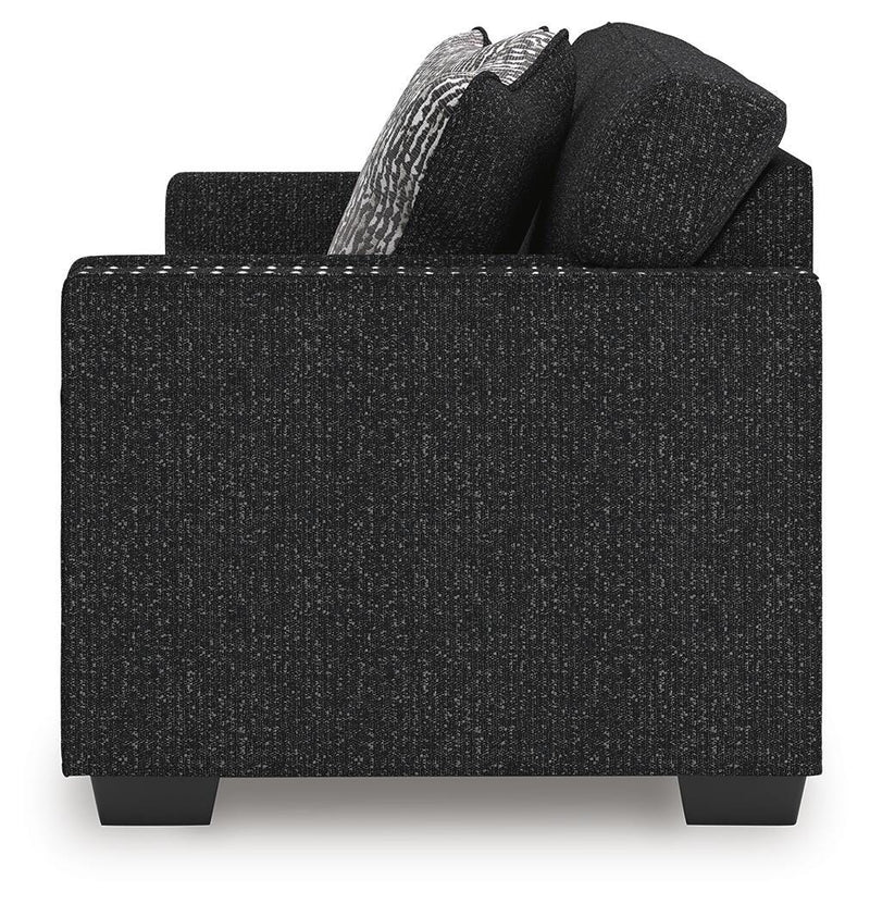 Ashley Furniture Jasmine Peaks sofa with plush cushions and neutral fabric, shown from a side view in a modern living room setting.