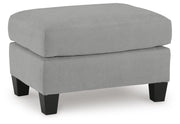 Ashley Furniture Adlai Ottoman with a soft beige fabric, featuring a plush cushioned top and wooden legs in a modern design.
