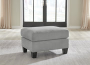 Ashley Furniture Adlai Ottoman in neutral fabric with a cushioned top and wooden block legs, versatile for living room decor.