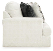 Ashley Furniture Karinne Sofa in a neutral fabric with plush cushions and wooden legs, shown from a side angle.