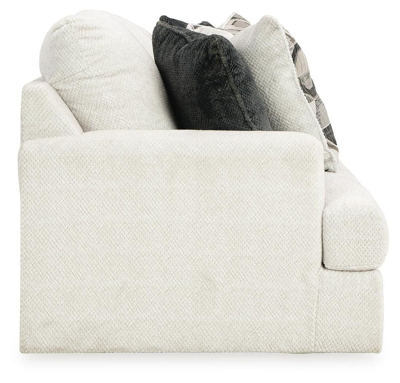 Ashley Furniture Karinne Sofa in a neutral fabric with plush cushions and wooden legs, shown from a side angle.