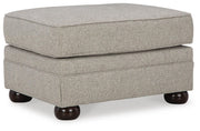 Ashley Furniture Gaelon Ottoman featuring a plush fabric surface and wooden legs, viewed from an angled perspective.