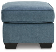 Ashley Furniture Cashton Ottoman with plush fabric and wooden legs, shown in a stylish side view.
