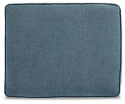 Ashley Furniture Cashton Ottoman with a cushioned top and wooden legs, shown in a cozy living room setting.