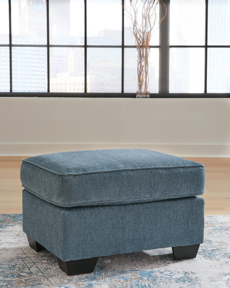 Ashley Furniture Cashton Ottoman with plush upholstered top and wooden legs, perfect for living room decor.