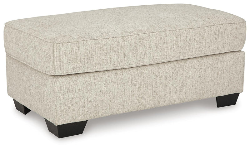 Ashley Furniture Heartcort Ottoman with soft fabric upholstery and wooden legs, shown from an angled view.