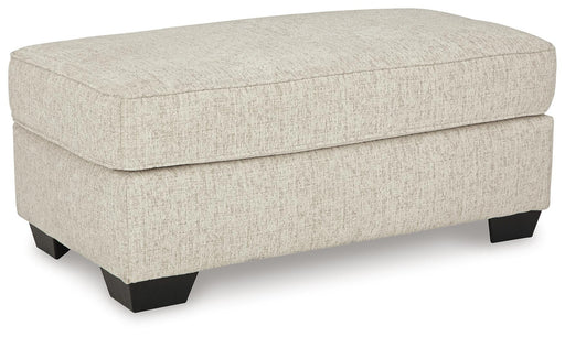 Ashley Furniture Heartcort Ottoman with soft fabric upholstery and wooden legs, shown from an angled view.