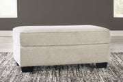 Ashley Furniture Heartcort Ottoman with soft cushioned top and wooden legs, ideal for living room decor.