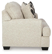 Ashley Furniture Heartcort loveseat with plush beige fabric and cushioned armrests, shown from a side angle.
