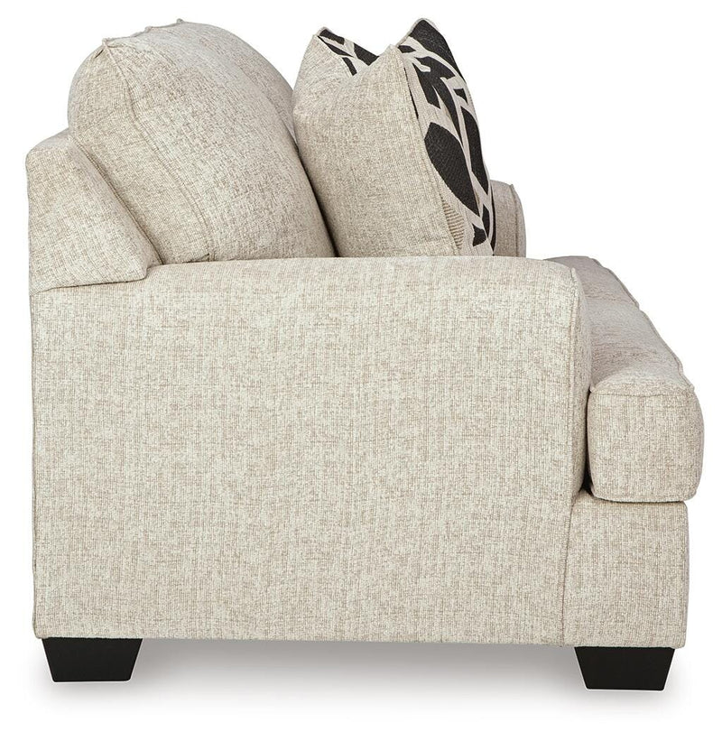 Ashley Furniture Heartcort loveseat with plush beige fabric and cushioned armrests, shown from a side angle.