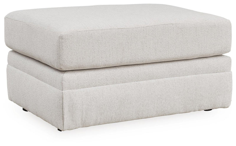 Ashley Furniture Maitelynn Ottoman in textured fabric, angled view showing sturdy wooden legs and plush cushioning.