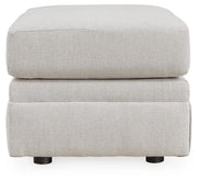 Ashley Furniture Maitelynn Ottoman with soft fabric upholstery and wooden legs, shown from a side angle.