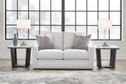 Ashley Furniture Maitelynn loveseat with plush fabric and tufted backrest, featuring cushioned armrests and wooden legs.