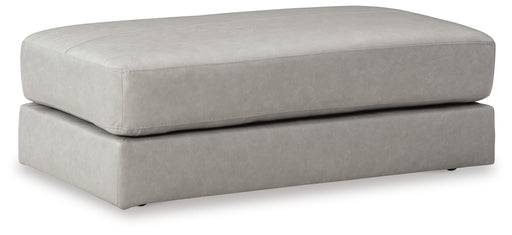 Ashley Furniture Amiata oversized accent ottoman with plush fabric and tufted top, shown from an angled side view.