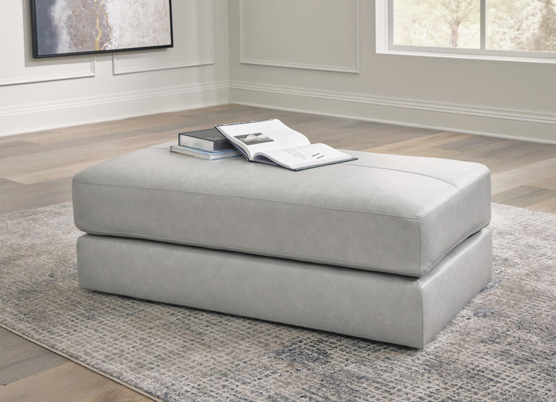 A beige Amiata oversized accent ottoman by Ashley Furniture with plush fabric and a soft, rounded design for living room decor.