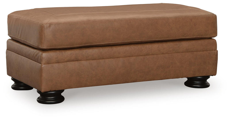 Ashley Furniture Carianna Ottoman with plush fabric and wooden legs, shown from an angled view.