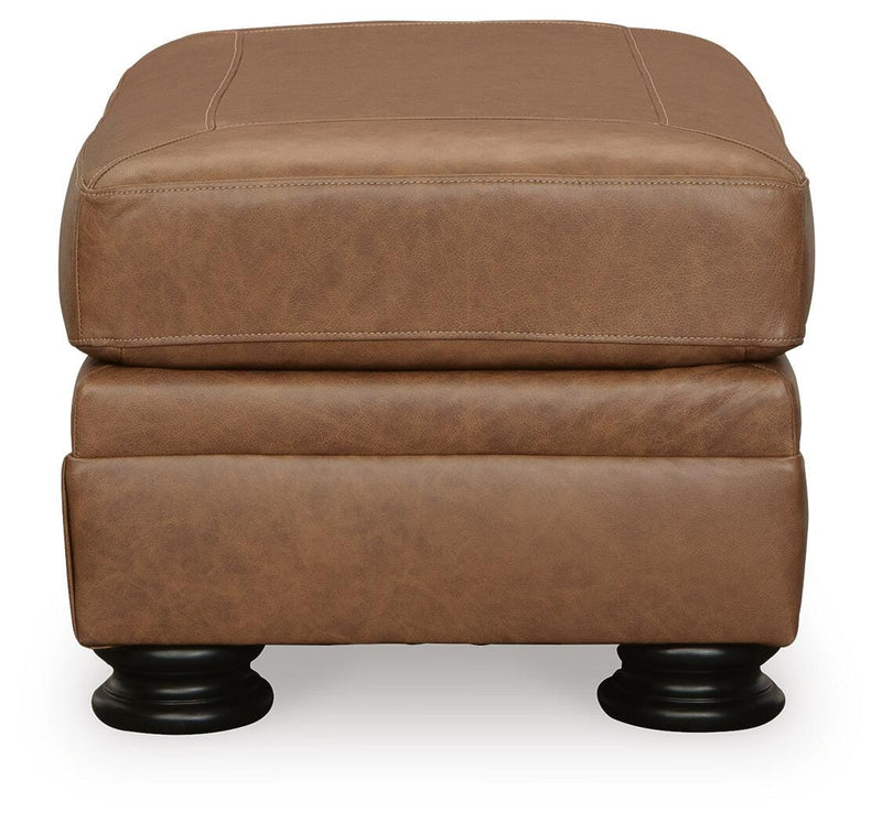Ashley Furniture Carianna Ottoman showing a plush fabric top and wooden legs, placed as a versatile living room accent piece.