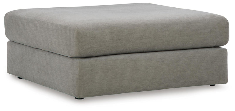 Ashley Furniture Avaliyah oversized accent ottoman with plush fabric and sturdy wooden legs, shown from a side angle.