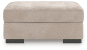 Ashley Furniture high profile ottoman with cushioned top and dark wooden legs, shown in a sleek, modern living room setting.