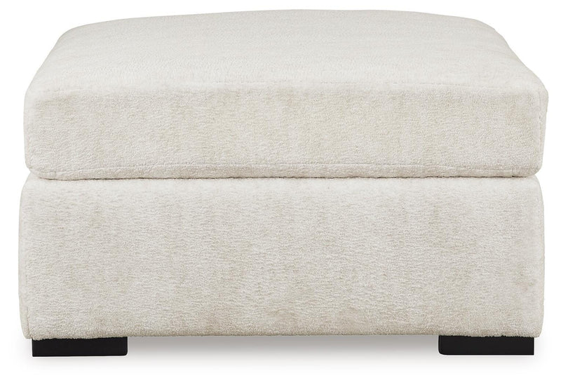 Ashley Furniture Chessington oversized accent ottoman with tufted fabric and wooden block legs, shown from a side angle.