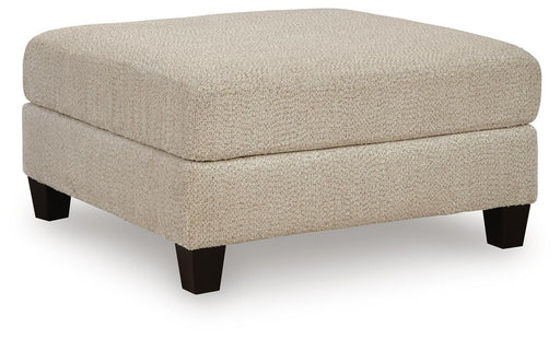 Steelwater Retreat oversized accent ottoman by Ashley Furniture, shown from an angle with plush fabric and sturdy wooden legs.