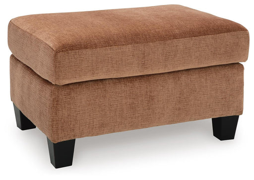 Ashley Furniture Amity Bay Ottoman with fabric upholstery, shown from an angled view, featuring a cushioned top and wooden legs.