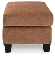 Ashley Furniture Amity Bay Ottoman with plush fabric and storage space, shown from a side angle in a cozy living room setting.