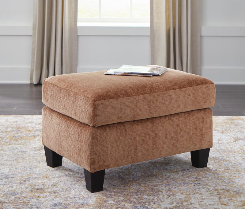 Ashley Furniture Amity Bay Ottoman featuring a plush fabric top and wooden legs, perfect for living room decor.