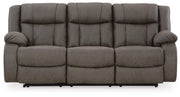 Ashley Furniture First Base Reclining Sofa in neutral fabric, showing plush cushions and reclining mechanism from a front view.