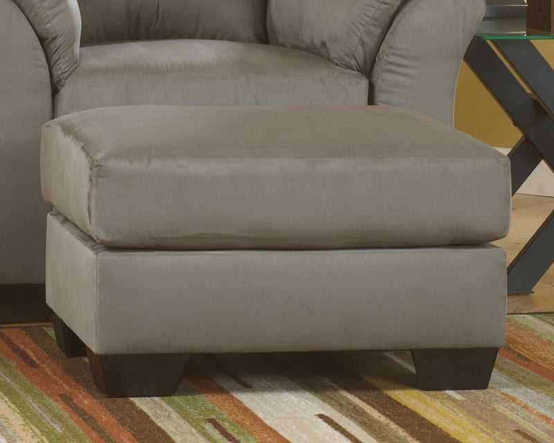 Ashley Furniture Darcy Ottoman in beige fabric with tufted top and wooden block legs, ideal as a versatile living room accent piece.